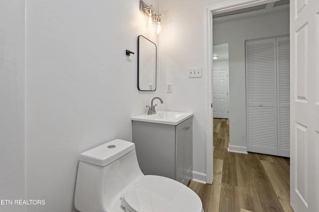 bathroom with hardwood / wood-style floors, vanity, and toilet