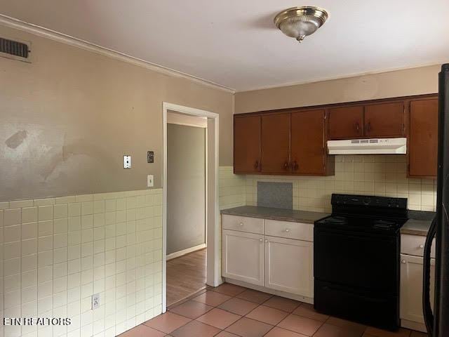 kitchen with decorative backsplash, black electric range, and light tile patterned flooring