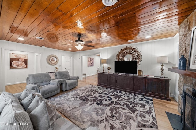 living room featuring ceiling fan, a fireplace, wooden ceiling, and light wood-type flooring