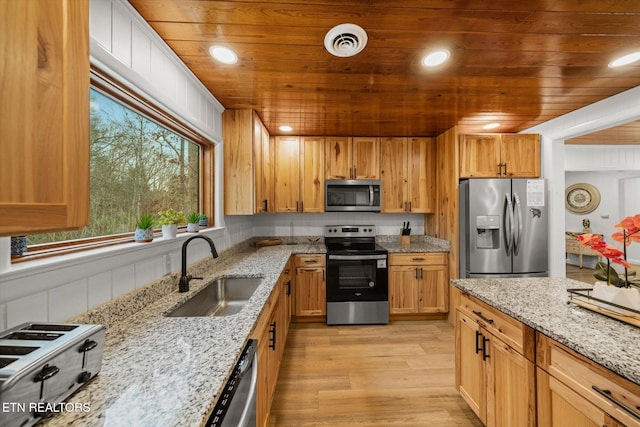 kitchen with light stone countertops, stainless steel appliances, light hardwood / wood-style floors, and sink