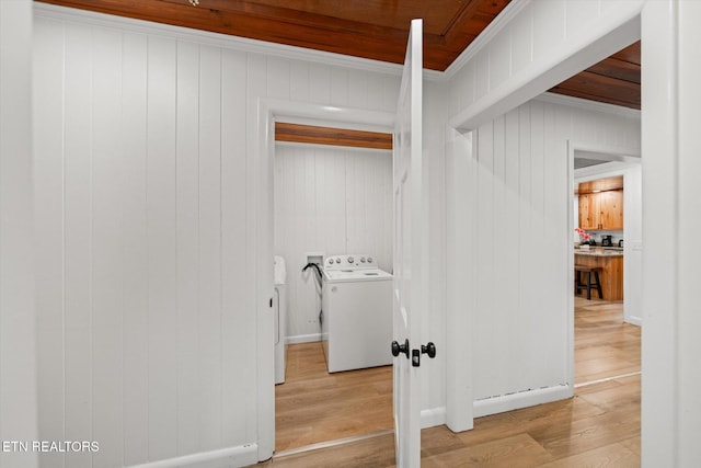 clothes washing area featuring hardwood / wood-style floors, wood walls, crown molding, and washer / clothes dryer