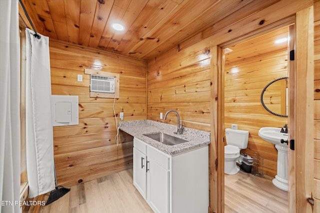 laundry room featuring a wall mounted air conditioner, wooden ceiling, sink, wooden walls, and light hardwood / wood-style floors