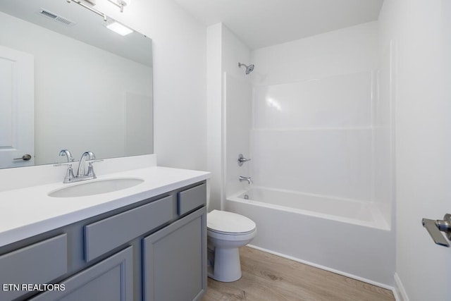 full bathroom with hardwood / wood-style floors, toilet, shower / bathing tub combination, and vanity