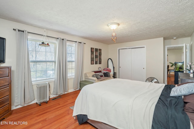 bedroom featuring radiator, a closet, a textured ceiling, and hardwood / wood-style flooring