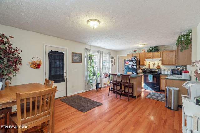 kitchen featuring black appliances, light hardwood / wood-style floors, and a textured ceiling