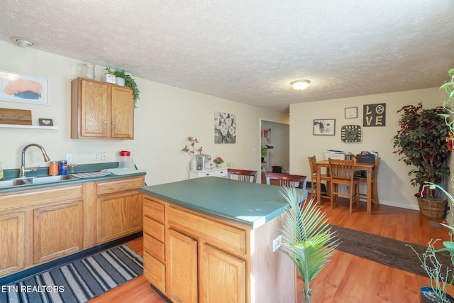 kitchen featuring sink, a center island, a textured ceiling, and light wood-type flooring