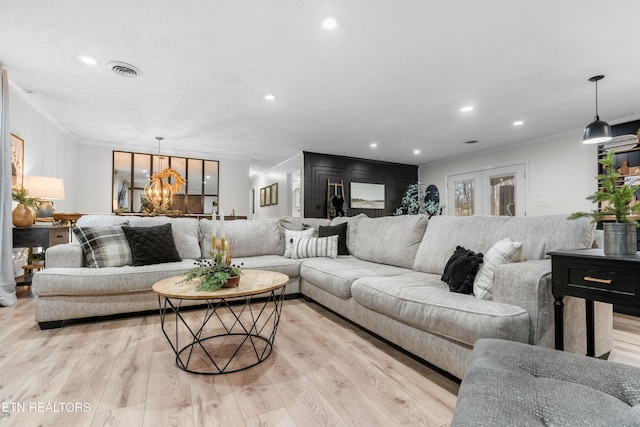 living room featuring light wood-type flooring, crown molding, and a notable chandelier