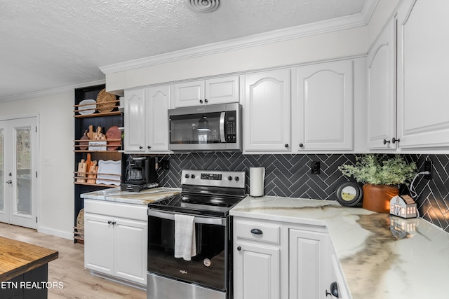 kitchen with a textured ceiling, white cabinetry, backsplash, and appliances with stainless steel finishes