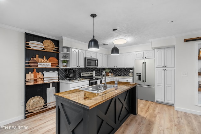 kitchen with white cabinets, sink, stainless steel appliances, and a center island with sink