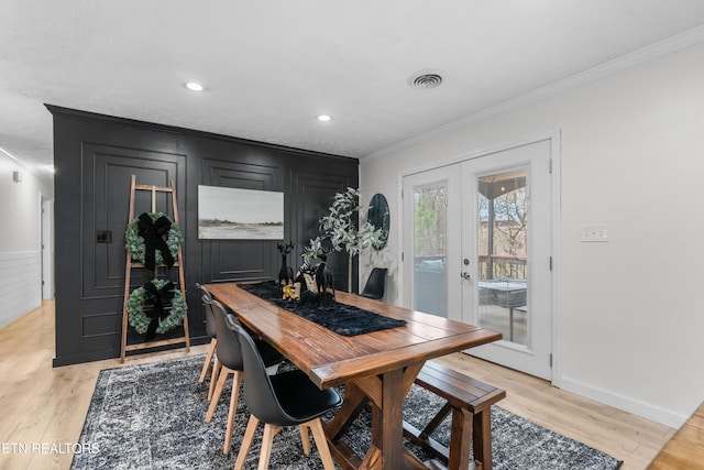 dining room with light wood-type flooring, crown molding, and french doors