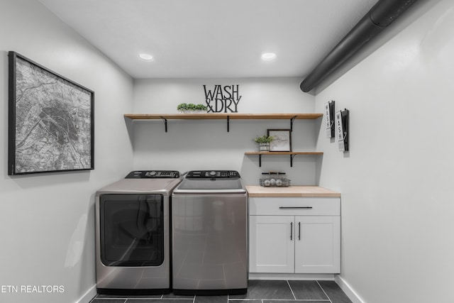 washroom featuring washer and dryer, dark tile patterned floors, and cabinets