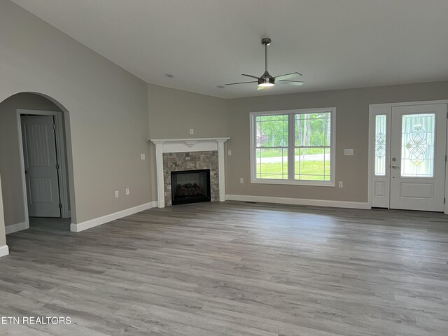 150 Hunterwood Ln, Fairfield Glade, TN 38558 - unfurnished living room featuring a ceiling fan, baseboards, light wood finished floors, a tile fireplace, and arched walkways