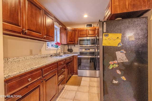 kitchen with light stone countertops, sink, light tile patterned floors, and appliances with stainless steel finishes