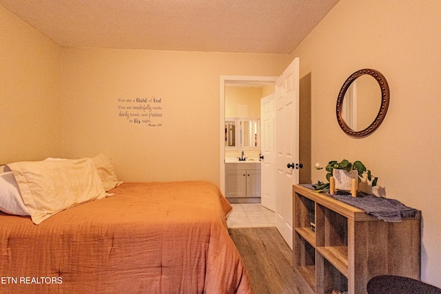 bedroom with wood-type flooring, sink, and connected bathroom