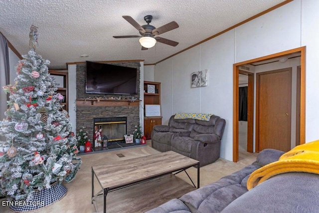 living room featuring ceiling fan, a stone fireplace, ornamental molding, and a textured ceiling