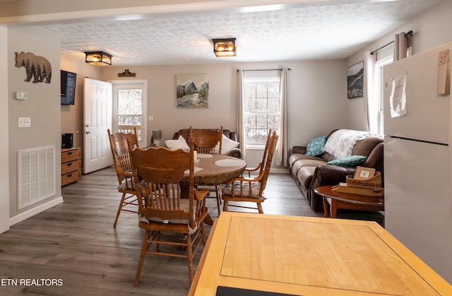 dining room with dark hardwood / wood-style floors and a textured ceiling