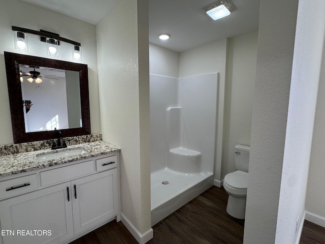 bathroom featuring hardwood / wood-style flooring, toilet, vanity, and walk in shower