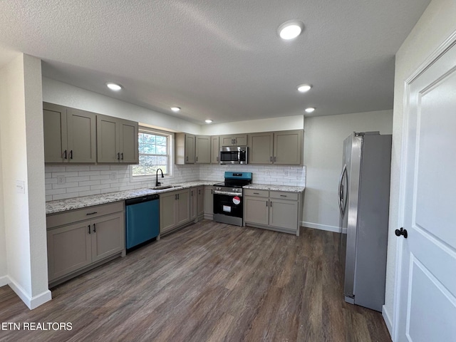 kitchen featuring dark hardwood / wood-style flooring, sink, light stone counters, and appliances with stainless steel finishes