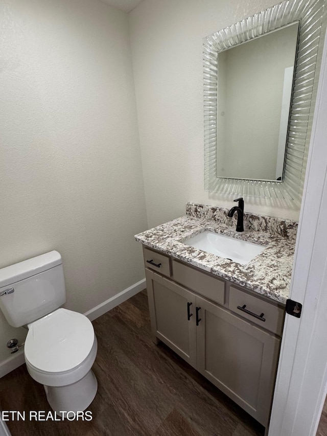 bathroom with hardwood / wood-style flooring, vanity, and toilet