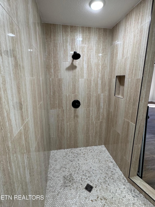 bathroom with a tile shower and a textured ceiling