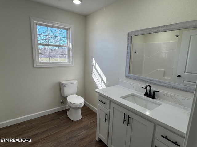 bathroom with hardwood / wood-style flooring, vanity, toilet, and a shower