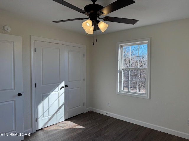 unfurnished bedroom with ceiling fan, dark hardwood / wood-style flooring, and a closet