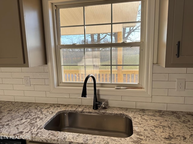 interior details featuring light stone countertops, sink, and decorative backsplash