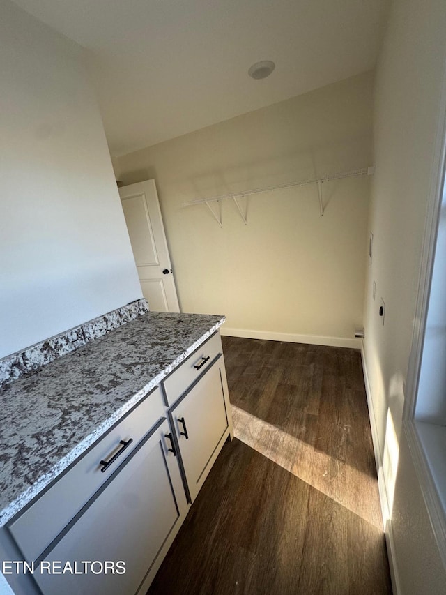 clothes washing area with dark wood-type flooring