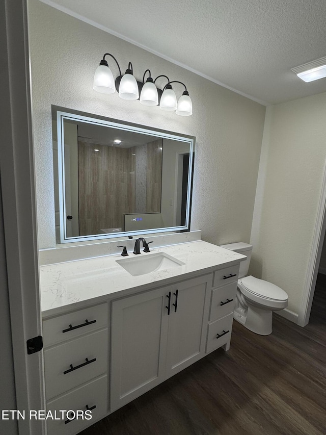 bathroom featuring vanity, wood-type flooring, toilet, and a textured ceiling