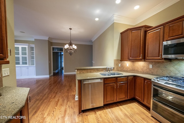 kitchen featuring kitchen peninsula, light stone counters, stainless steel appliances, sink, and a notable chandelier