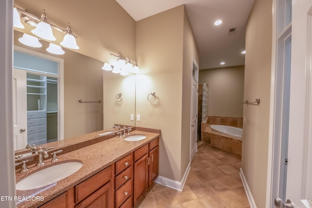 bathroom with tile patterned floors, vanity, and a relaxing tiled tub