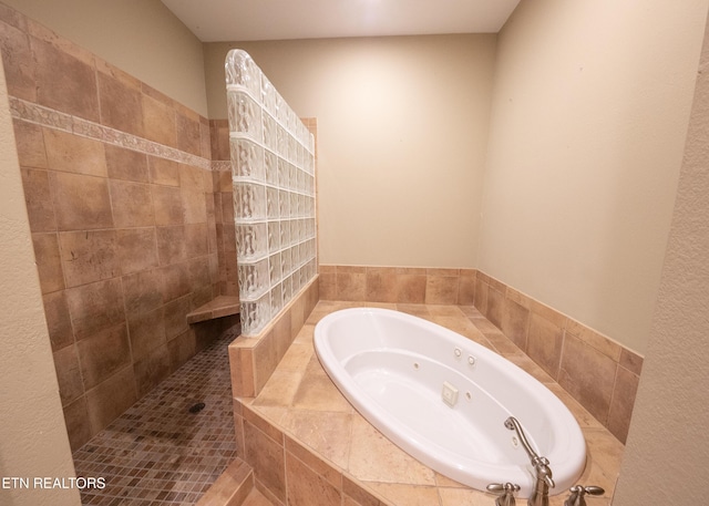 bathroom with a relaxing tiled tub and tile patterned floors