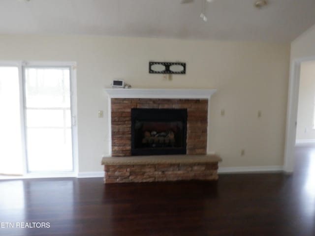 unfurnished living room featuring ceiling fan, a fireplace, dark wood-type flooring, and lofted ceiling