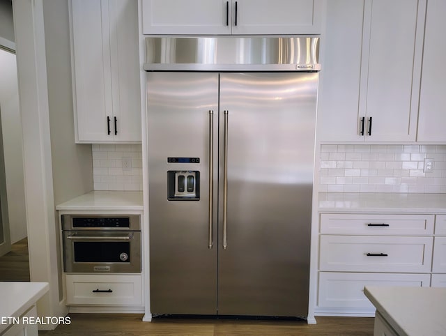 kitchen featuring white cabinets, decorative backsplash, and stainless steel appliances