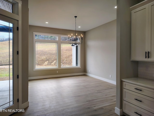 unfurnished dining area with light hardwood / wood-style floors and an inviting chandelier