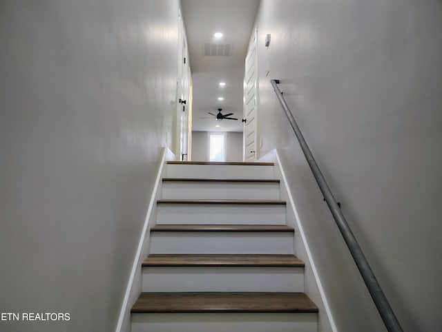 stairway featuring ceiling fan