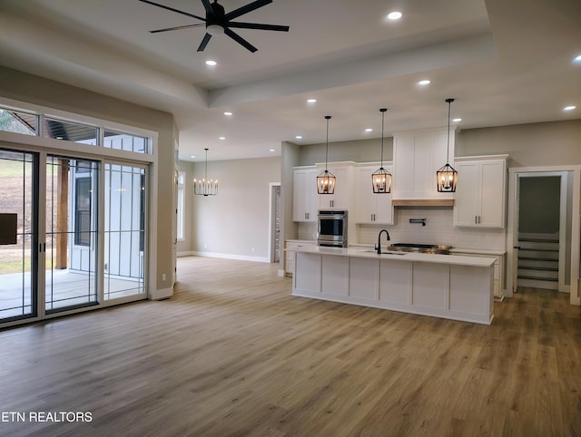 kitchen with white cabinetry, stainless steel appliances, and a large island with sink