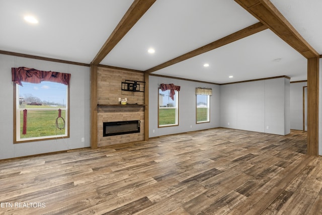 unfurnished living room featuring beam ceiling, wood-type flooring, a fireplace, and ornamental molding