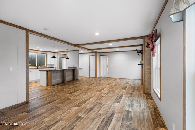 unfurnished living room featuring beamed ceiling, wood-type flooring, and sink