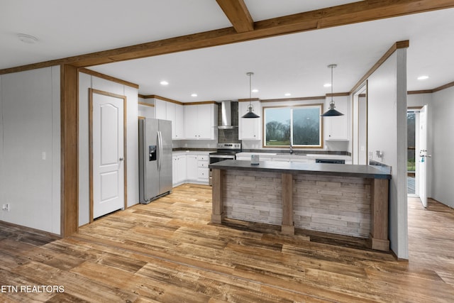 kitchen featuring pendant lighting, white cabinets, wall chimney range hood, sink, and appliances with stainless steel finishes