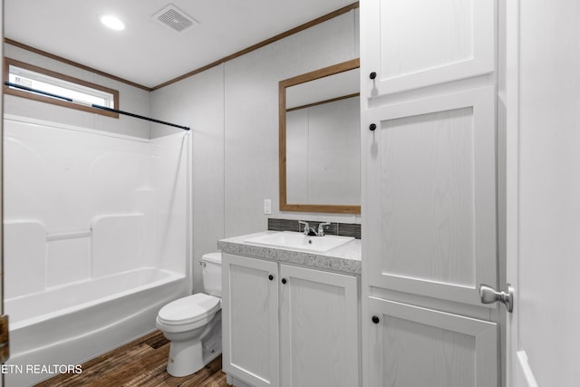 full bathroom with hardwood / wood-style floors, vanity, washtub / shower combination, toilet, and ornamental molding