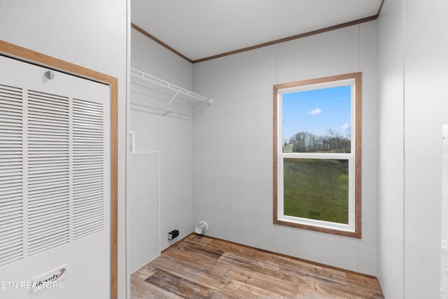 laundry area with light hardwood / wood-style floors and crown molding