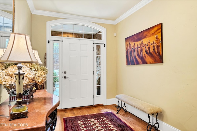 entrance foyer with crown molding, a healthy amount of sunlight, and hardwood / wood-style floors