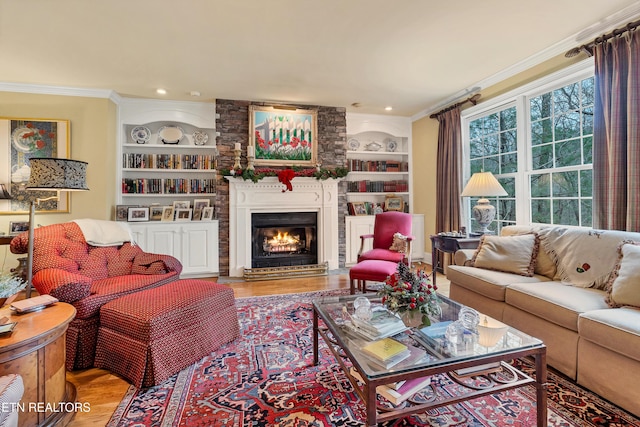 living room featuring ornamental molding, a large fireplace, built in features, and light hardwood / wood-style floors