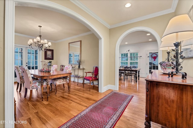 dining area with ornamental molding, an inviting chandelier, and light hardwood / wood-style flooring