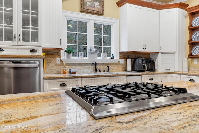 kitchen featuring sink, light stone counters, stainless steel appliances, decorative backsplash, and white cabinets