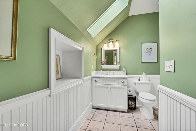 bathroom with vanity, lofted ceiling with skylight, tile patterned floors, and toilet