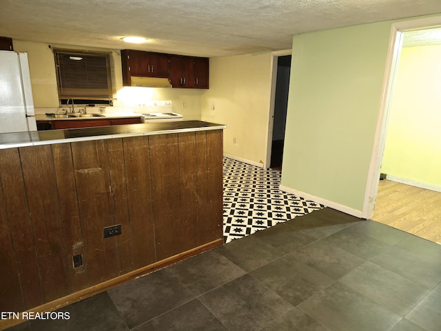 kitchen featuring range, sink, a textured ceiling, white fridge, and dark brown cabinetry