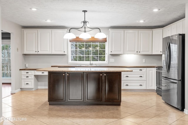 kitchen featuring decorative light fixtures, white cabinetry, light tile patterned floors, range, and stainless steel fridge with ice dispenser