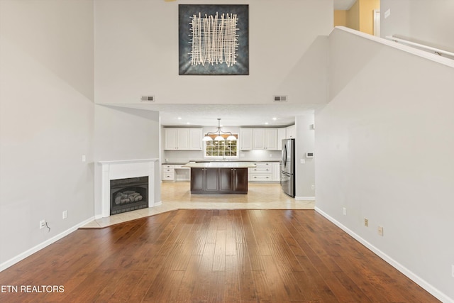 unfurnished living room with a high ceiling and light wood-type flooring